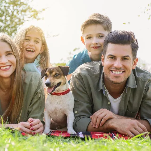 Une famille allongée dans l’herbe avec son chien